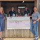 Four members of Trevaskis Farm team happily receiving a large cheque for £40,000 from Erica Vitai, in their fruit sale shed.